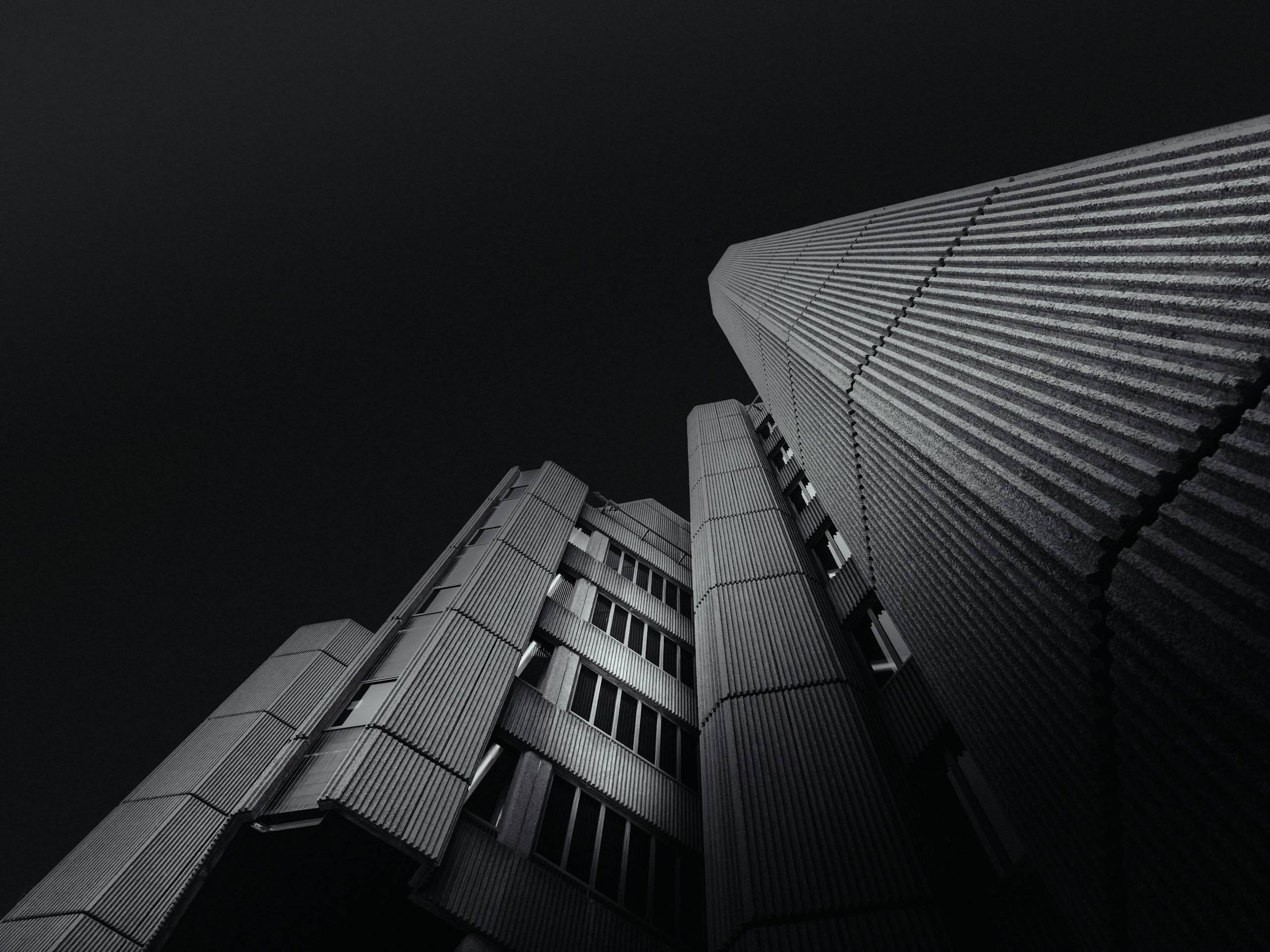 Fachada de edifício corporativo vista de baixo, em tons escuros
